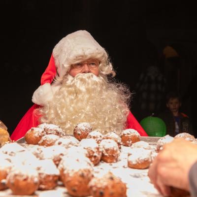 Kerstman achter tafel met oliebollen